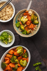 Brown rice with baked broccoli and sweet potato, dark background, top view. Healthy vegan food concept.