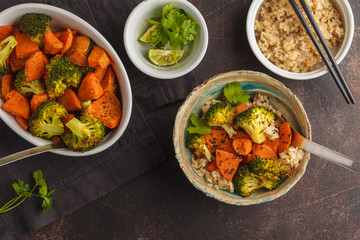 Brown rice with baked broccoli and sweet potato, dark background, top view. Healthy vegan food concept.