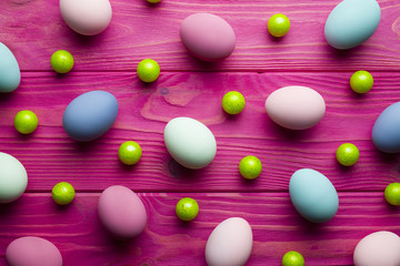 Colored Easter eggs and green balls on pink wooden background
