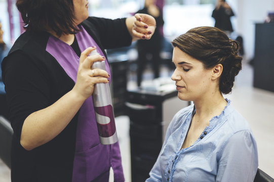 Hairdresser applying hair spray to a bride