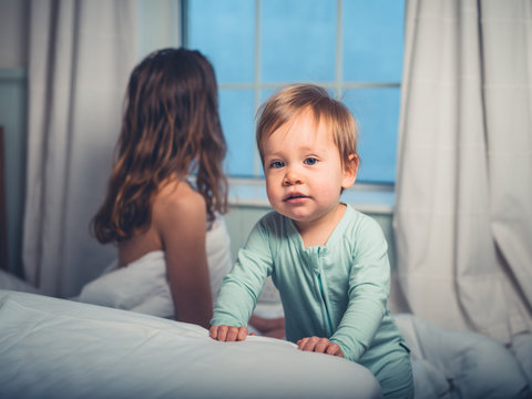 Little boy in bedroom with mother looking out the window
