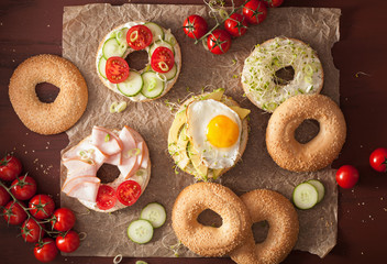 variety of sandwiches on bagels: egg, avocado, ham, tomato, soft cheese, alfalfa sprouts