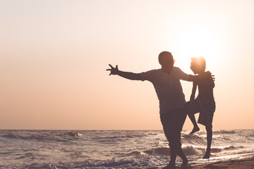 Fototapeta premium Father and son playing on the beach at the sunset time.