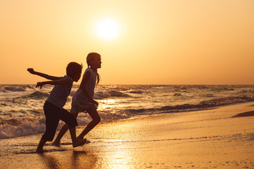 Happy children playing on the beach at the sunset time.