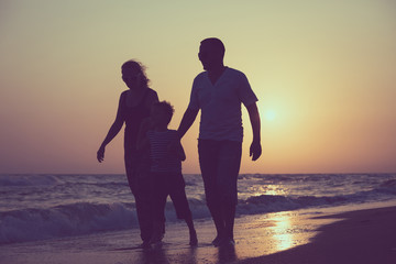 Fototapeta premium Father mother and son playing on the beach at the sunset time.