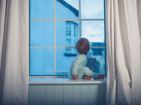 Little boy on window sill in the morning