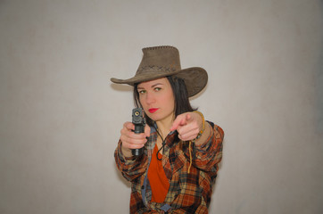 cowboy girl with pistol finger gesture you, on grey background