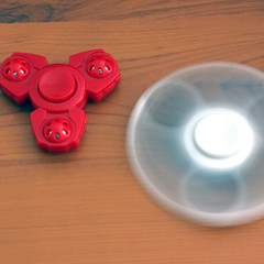 Two spinners on a wooden background. Red and white spinners. Toys