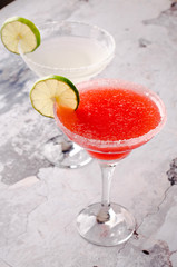 two classic and strawberry margarita, white and red alcoholic cocktail with decoration of salt on the edge of the glass with fresh lime, lemon, daiquiri on gray background restaurant. Bar alcohol menu