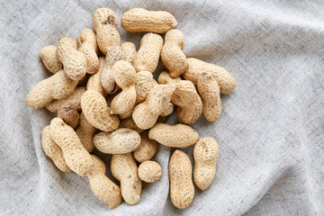 Heap of peanuts on light tablecloth, close-up, shallow depth of field, selective focus, macro