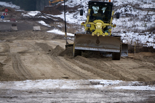 Motor grader with a blade performs the layout of a road crushed stone gravel base .