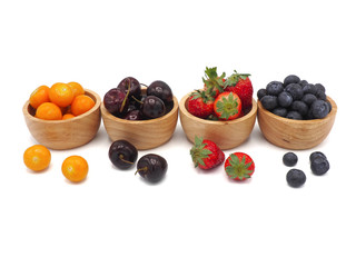 Fresh summer fruits, Cherry, strawberry, cape gooseberry and blueberry in wooden bowl isolated on white background.
