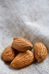 Heap of almond nuts on light tablecloth, close-up, shallow depth of field, selective focus, macro