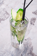 Delicious refreshing white alcoholic cocktail with fresh cucumber in a glass on gray background restaurant. Bar alcohol menu, summer drink. Homemade green lemonade, water