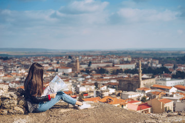 Young girl standing in front of beautiful city view and looking at the map.Panoramic view