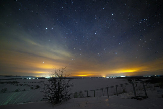 Bright starry night sky above the snowy landscape in the valley of the hills.