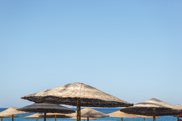 Straw umbrellas on the beach against the sea and sky