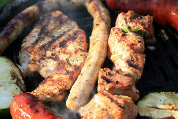 A set of meats baked on the grill during a family picnic in free time. Summer relaxation in the open air.