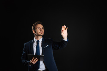 Point of vision. Concentrated handsome unshaken man holding the tablet holding hand up and touching to invisible object.