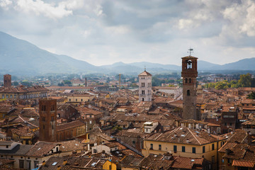 View of Torre Delle Ore from top of Guinigi Tower, Lucca, Tuscany, Italy. Scenic city panoramic overview picturesque travel postcard. - obrazy, fototapety, plakaty
