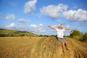 Naklejka na ściany i meble Little smiling boy in wheat field on a summer sunny day