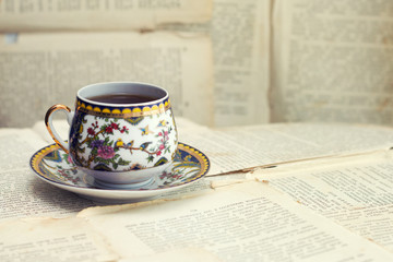 An old cup of coffee on the background of old sheets from the book
