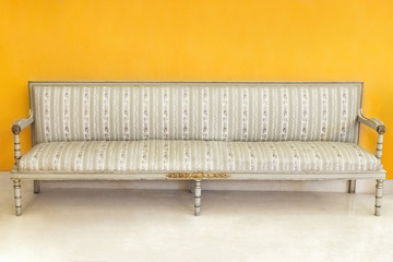 Beautiful classic retro sofa with striped upholstery near the yellow wall