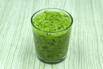 glass of kiwi juice with fresh fruits on wooden table .