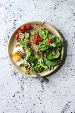 Vegetarian sandwiches with avocado, poached egg, spinach, cherry tomatoes on whole grain toast bread on ceramic plate with textile napkin over white marble background. Top view, space