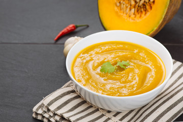 Pumpkin soup in a bowl with garlic and parsley herbs