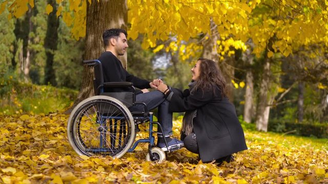 disability, love, romance - man in wheelchair at the park with his girlfriend