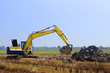 excavator backhoe working in the digging a soil to adjust the postharvest areas in the rice fields. agriculture machinery for modern agriculture industry.