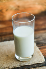 glass of milk with napkin on old wooden table