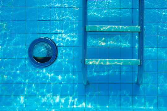 Underwater swimming pool wall with ladder and light bulb