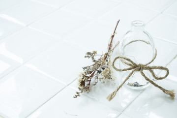 Empty transparent vintage bottle with rope and dried flower on white dining table