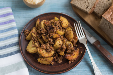 Fried potato wedges with bolognese sauce on a rustic wooden background