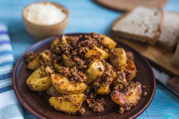 Fried potato wedges with bolognese sauce on a rustic wooden background