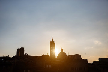 Picturesque silhouette view of Siena Cathedral Santa Maria Assunta (Duomo) at sunset golden hour, Tuscany, Italy. Scenic travel destiantion postcard.