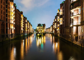 long time exposure shot of canal amidst illuminated buildings in old warehouse district Speicherstadt in Hamburg, Germany at night