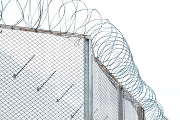 Metal fence of prison with barbwire on top