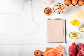 Ketogenic low carbs diet concept. Healthy balanced food with high content of healthy fats. Diet for the heart and blood vessels. Organic ingredients, white background, copy space top view, notepad