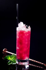 Delicious blackberry cocktail with berry juice, green mint ice cubes in a glass on black background. Exotic red summer drink. Bar alcohol menu, enjoy. Sweet lemonade