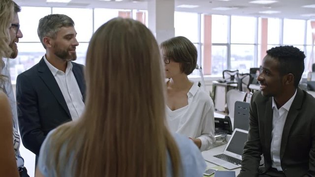 Group of colleagues standing in circle in office and assigning roles and responsibilities for new project