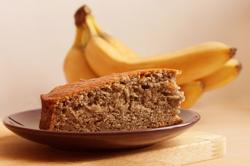 Banana pie close up on a plate with a bunch of babanas around.