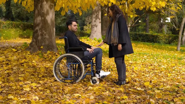 Disability, love Romanticism.woman at the park with  boyfriend in a wheelchair