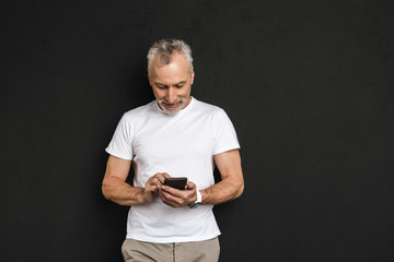 Cheerful handsome mature old man using mobile phone.