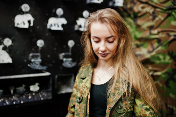 Military girl in camouflage uniform against army background on shooting range.