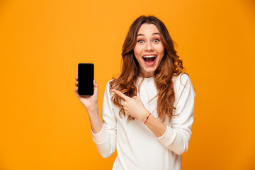 Surprised happy brunette woman in sweater showing blank smartphone screen