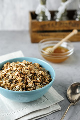 Homemade granola in a blue bowl on a linen napkin with a bottle of milk and honey. Food Photography of a healthy morning breakfast.