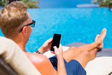 Man using smartphone by the pool.